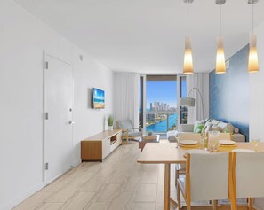 Een moderne woonkamer met een eethoek, grote ramen met uitzicht over de stad en een minimalistische inrichting.
