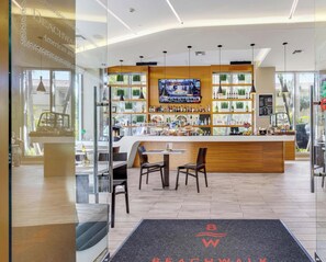 A modern bar area with a TV screen, wooden counter, and seating. - Intracoastal Escape · 2BR Beachwalk Resort (Hallandale Beach)