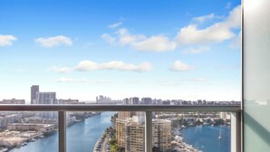 Un balcon avec vue sur la ville, donnant sur une rivière, un port de plaisance et des immeubles de grande hauteur.