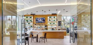 A bar area with a TV screen, shelves with bottles, and seating. - Beachwalk Studio | Pininfarina Design & Pool (Hallandale Beach)