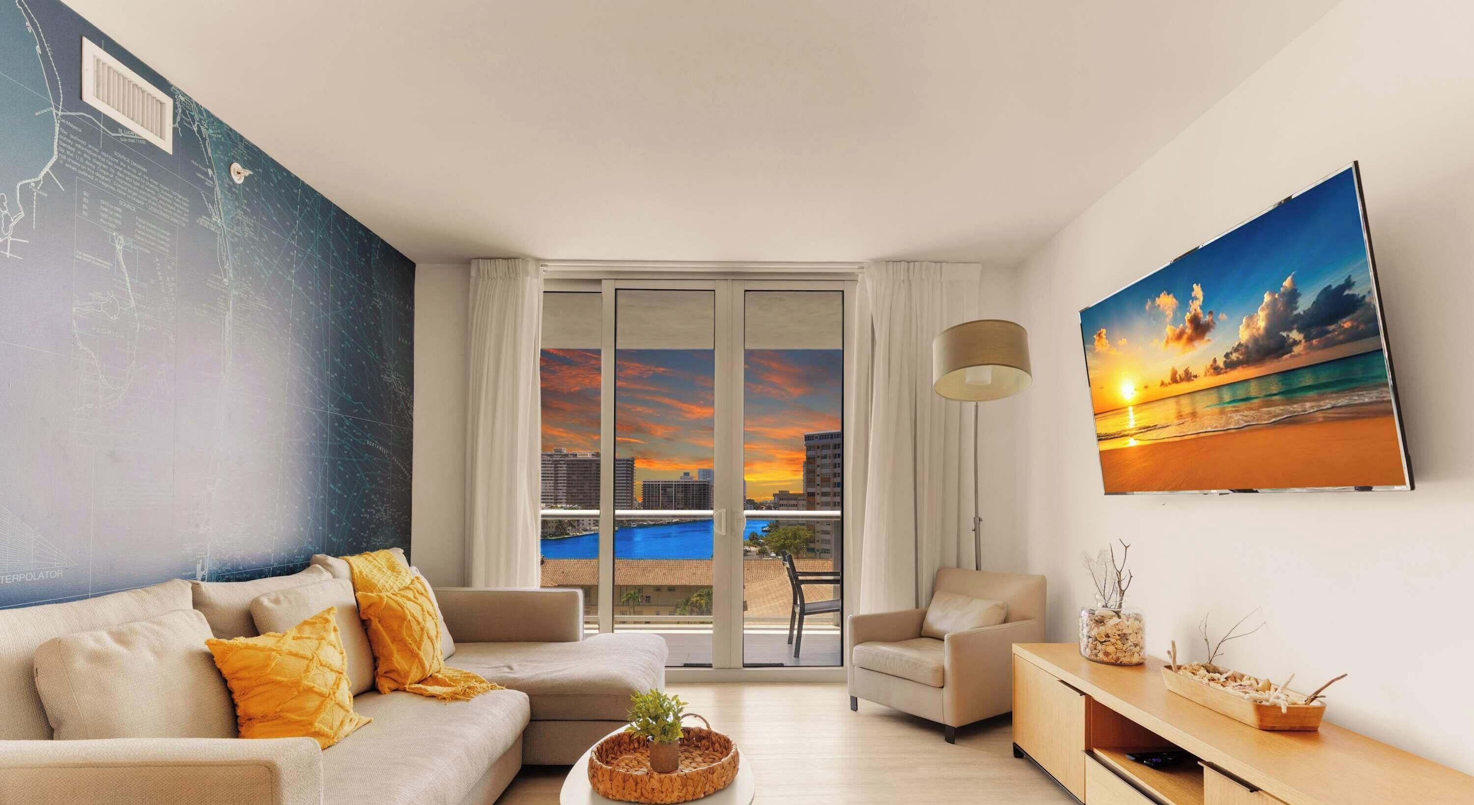 A modern living room with a sofa, armchair, and a painting of a sunset.