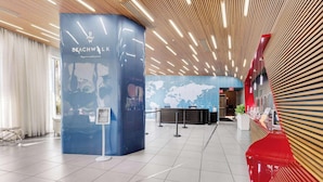 Eine moderne Lobby mit einer Rezeption, einer Weltkarte an der Wand und einem Schild, das darauf hinweist, dass Bade- und Strandkleidung nicht nötig ist.