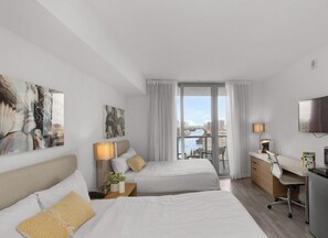 Ein Hotelzimmer mit Bett, Schreibtisch, Fernseher und Blick auf die Stadtlandschaft.