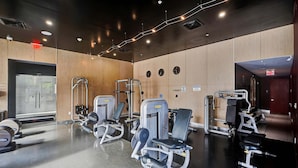 Ein Fitnessraum mit Trainingsgeräten, Holzwänden und einer Spiegelwand.