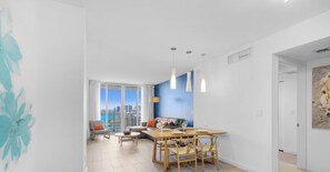Ein modernes Wohnzimmer mit Essbereich, großen Fenstern und Blick auf die Stadt.