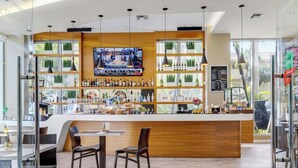 Zona de bar con mostrador de madera, asientos y una pantalla de televisión.