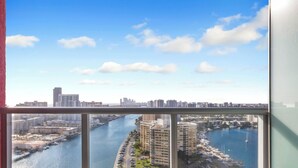 Un balcón con vista a la ciudad, sobre un río, un puerto deportivo y edificios altos.