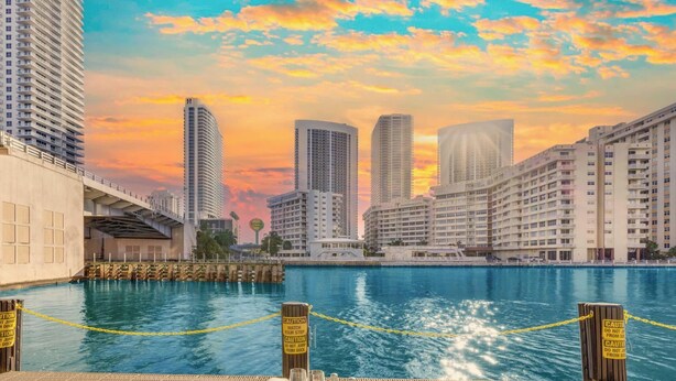 Zona de comedor frente al agua con vista al horizonte de la ciudad, un muelle y señales de precaución.