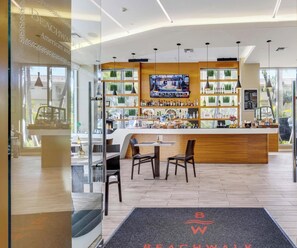 A modern bar area with a TV screen, wooden counter, and seating. - Upper Studio | Intracoastal & Miami Skyline (Hallandale Beach)