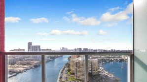 Un balcon avec vue sur la ville, donnant sur une rivière, un port de plaisance et des immeubles de grande hauteur.