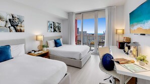 A hotel room with two beds, a desk with a computer, a large window with a city view, and artwork on the walls. - Modern Spacious Studio - Resort‑Style Experience (Hallandale Beach)