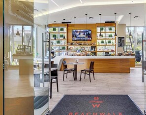 A modern bar area with a TV screen, wooden counter, and seating. - New! Stunning Bay View 2BR (Hallandale Beach)