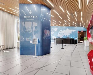 Eine moderne Hotelhalle mit einer gebogenen Rezeption, einer Weltkarte an der Wand und einer Holzzellentdecke.
