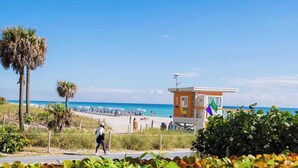 A beach with a lifeguard tower, beach umbrellas, and palm trees. - Bright Studio | Intracoastal View & Pool (Hallandale Beach)