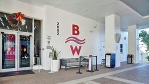 A hotel entrance with a glass door, a reception desk, and a sign indicating room rates. - Bright Studio | Intracoastal View & Pool (Hallandale Beach)