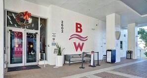 Ein Hotel Eingang mit Glastür, einem rot-weißen Logo und der Nummer 2602 an der Wand.
