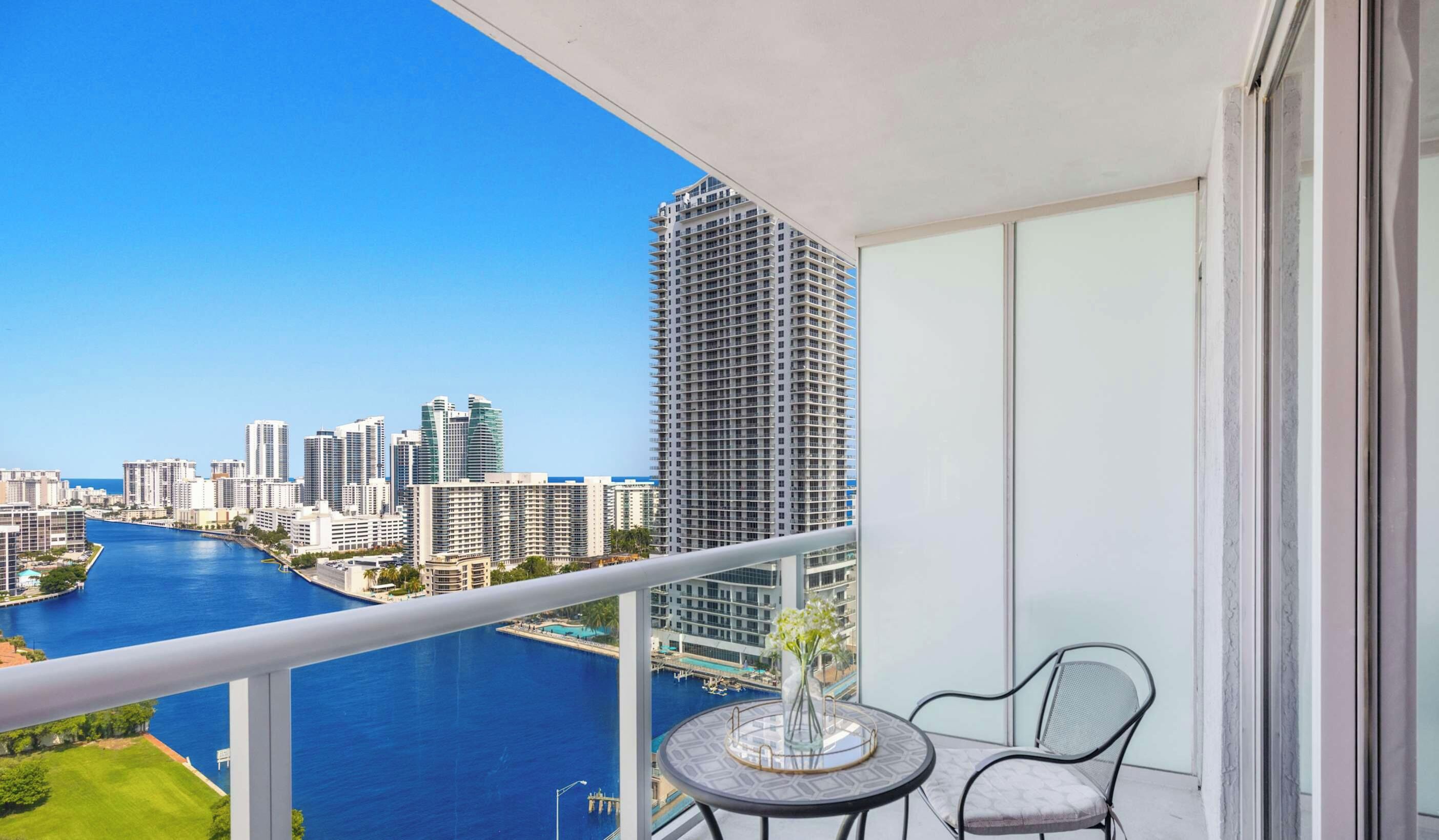 A balcony with a view of a river and high-rise buildings.