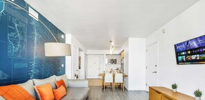 A modern living room with a sofa, a dining area, and a kitchen in the background. - Spacious 1BR · Intracoastal View · Resort & Pool (Hallandale Beach)