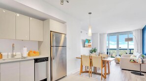 A modern kitchen with a stainless steel refrigerator and a dining area with a table and chairs. - Spacious 1BR · Intracoastal View · Resort & Pool (Hallandale Beach)