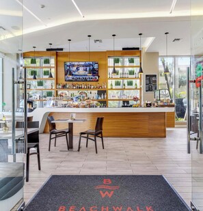 A modern bar area with a TV screen, wooden counter, and seating. - Spacious 1BR · Intracoastal View · Resort & Pool (Hallandale Beach)