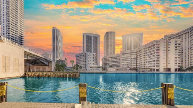 Zona de comedor frente al agua con vista al horizonte de la ciudad, un muelle y señales de precaución.