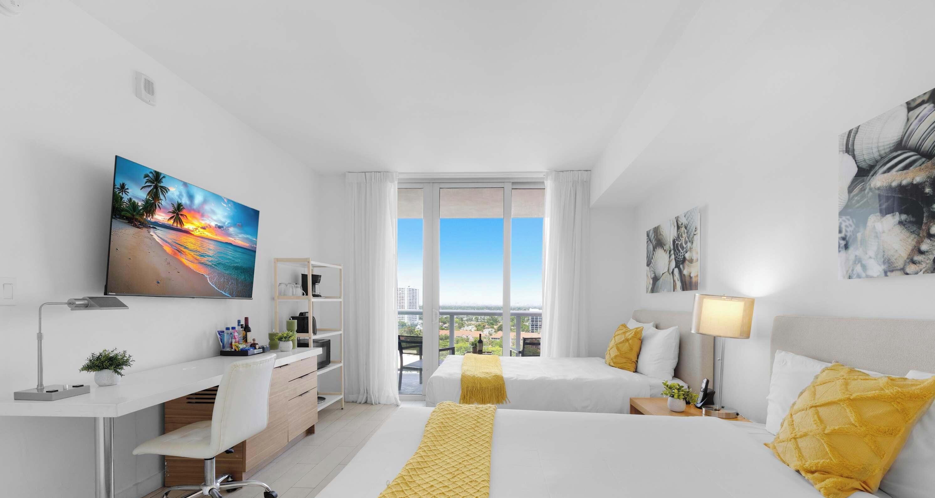 Une chambre d’hôtel équipée d’un lit, d’un bureau, d’une chaise, d’une télévision et d’une fenêtre donnant sur la ville.