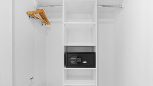 Un intérieur blanc avec un coffre-fort noir placé sur l’étagère inférieure.