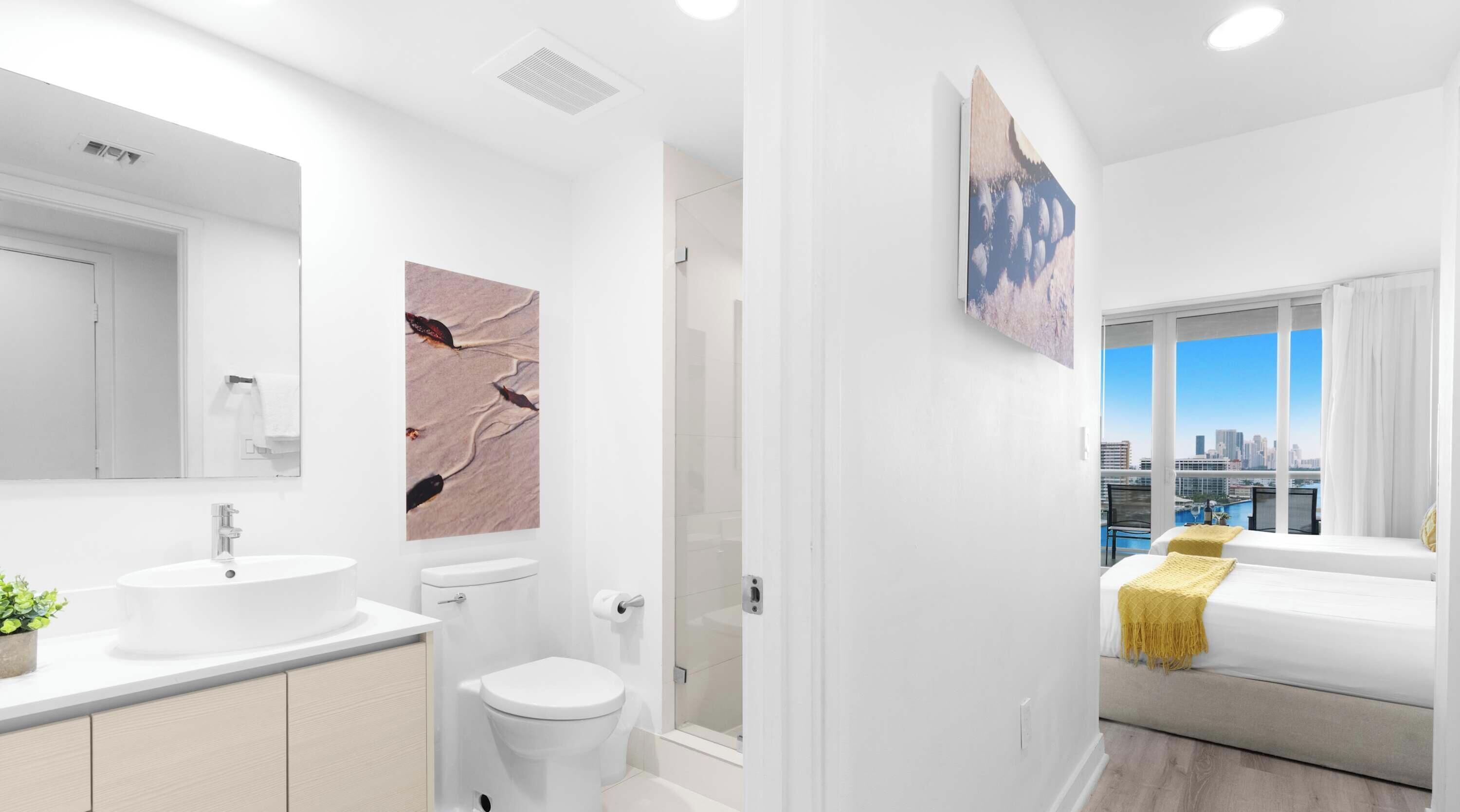 Un bagno moderno con uno specchio grande, un lavandino, il water e una doccia.