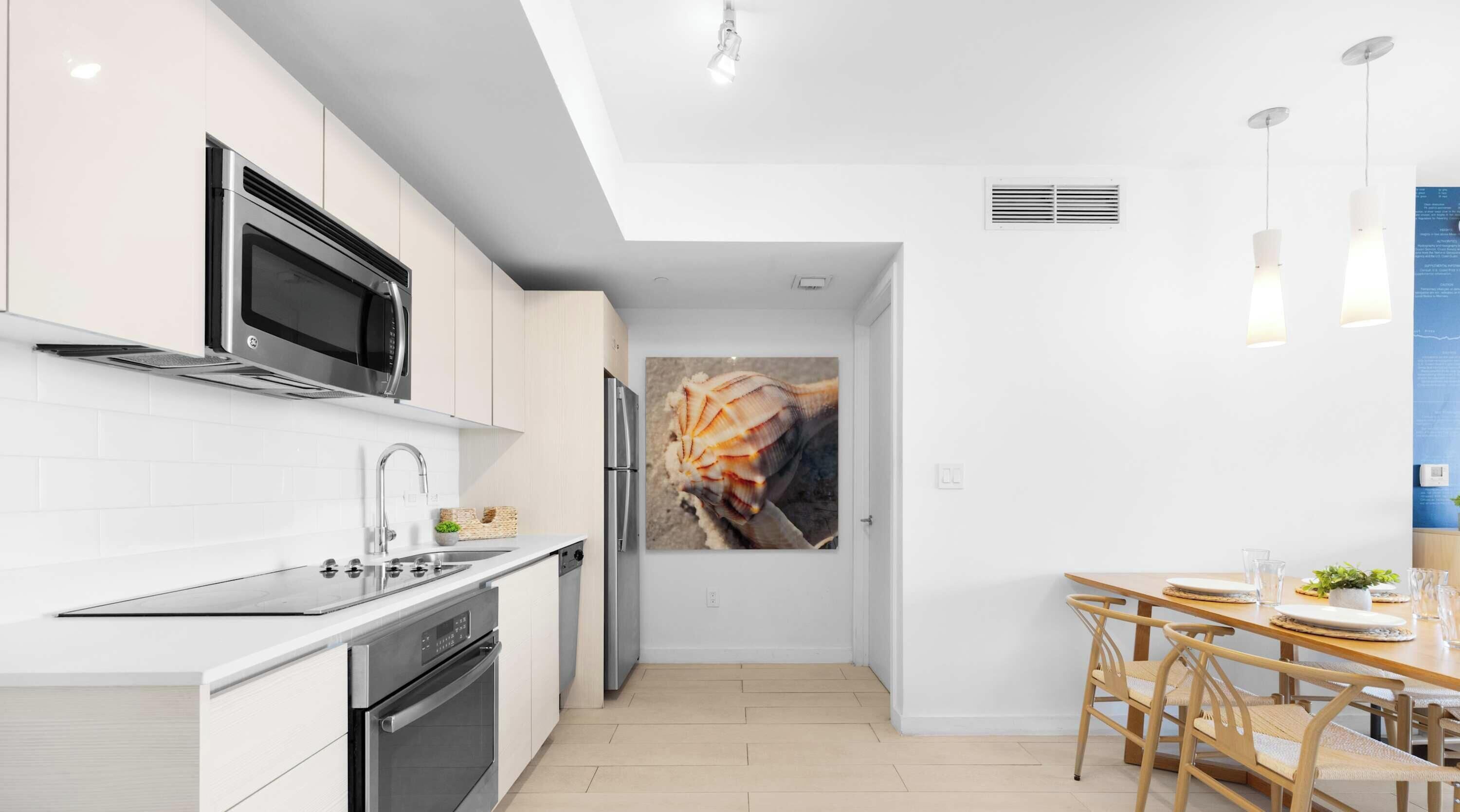 A modern kitchen with stainless steel appliances, a white tiled backsplash, and a dining area with a wooden table and chairs.
