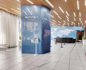 En modern hotellobby med en böjd receptionsdisk, en världskarta på väggen och en träpanel i taket.