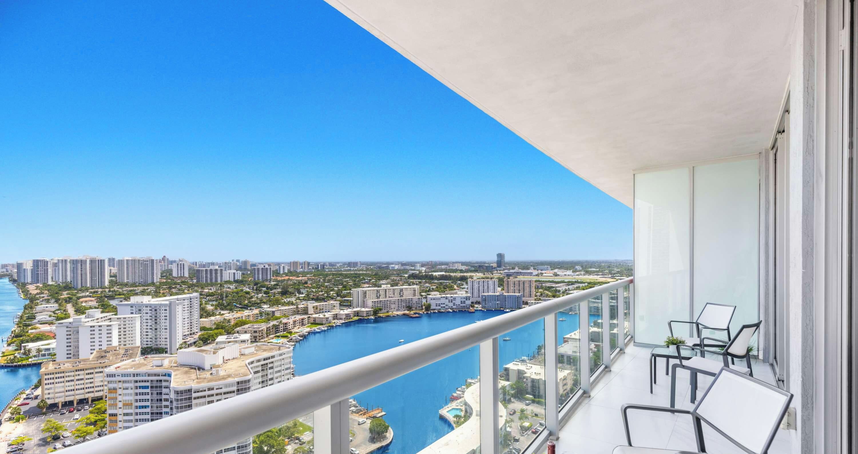 Een balkon met uitzicht op een jachthaven en stadsbeeld.