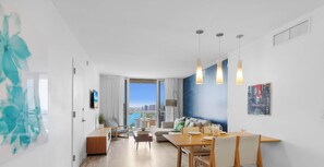 Ein modernes Wohnzimmer mit Essbereich, großen Fenstern und Blick auf die Stadt.