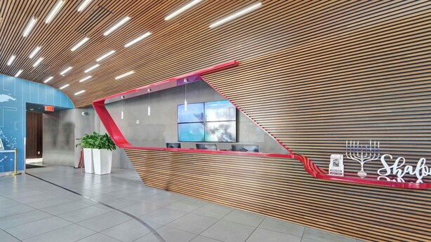 A modern reception area with a sloped ceiling, a reception desk, and a wall-mounted digital display. - Stylish Studio Near the Beach | Resort Life (Hallandale Beach)