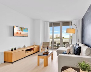 Ett modernt vardagsrum med en soffa, ett soffbord, en tv och en balkong med utsikt.