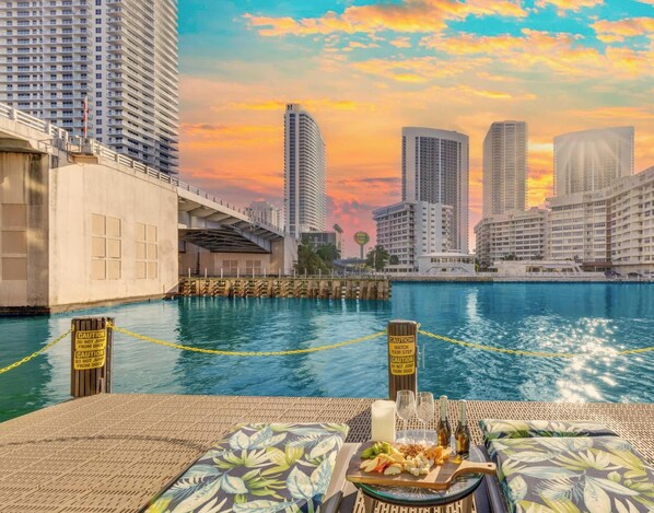 A waterfront hotel with high-rise buildings in the background, a swimming pool, and caution signs along the poolside. - Stylish 1BR Near the Beach  Resort Life (Hallandale Beach)