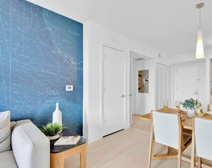 Ein modernes Interieur mit einer Wand im maritimen Stil, einem Essbereich und einem Flur, der zu Schlafzimmern führt.