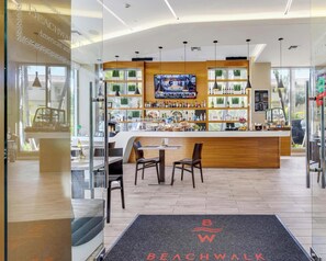 A modern bar area with a TV screen, wooden counter, and seating. - Beachwalk 1BR with Stunning Intracoastal View (Hallandale Beach)