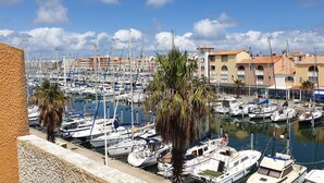 A marina with numerous boats docked, a building with a sign, and a clear sky. - 2 rooms, with balcony overlooking the port (Leucate)