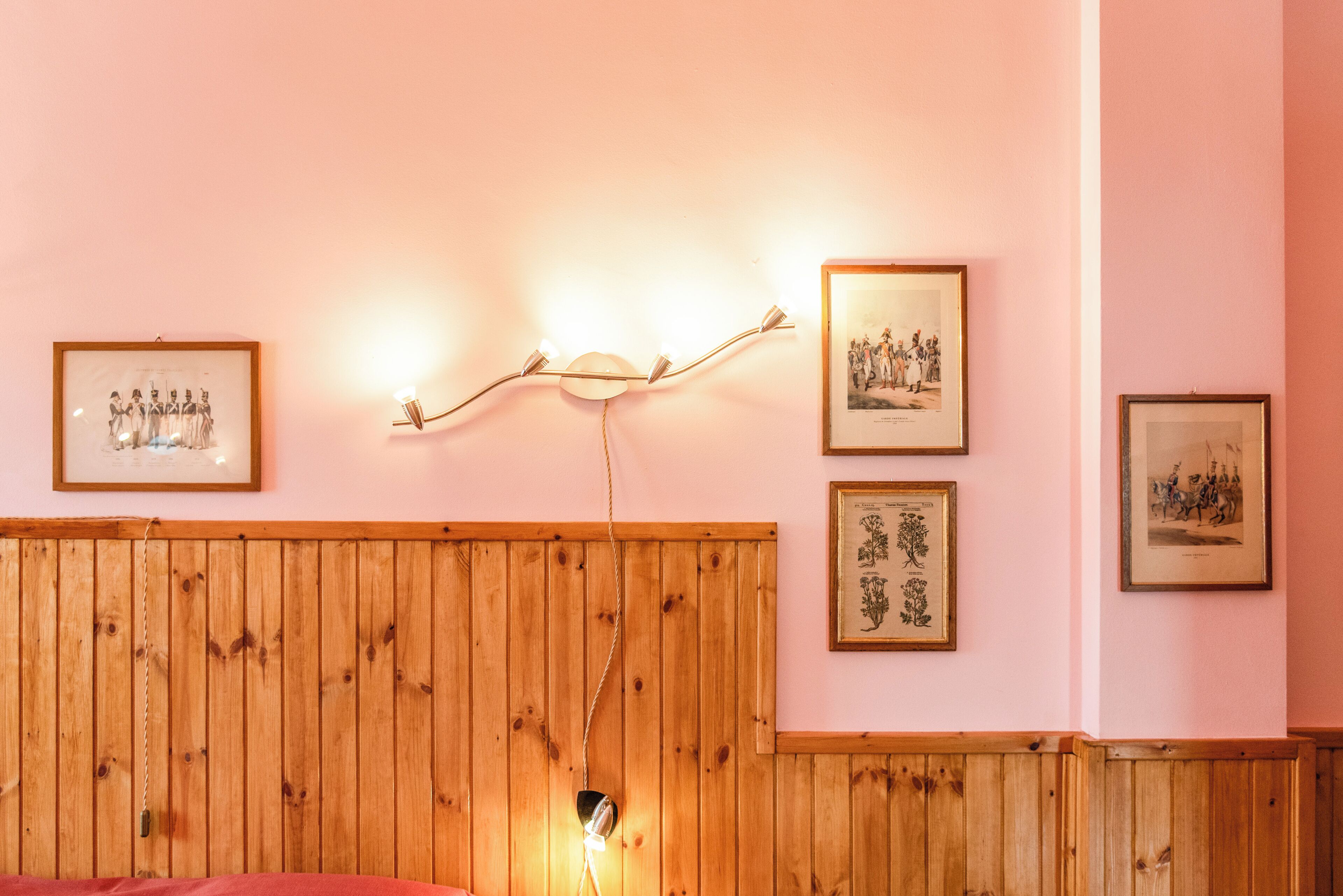 Una habitación con paneles de madera, cuadros enmarcados en la pared y una cama con cubierta roja.