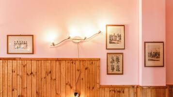 Una habitación con paneles de madera, cuadros enmarcados en la pared y una cama con cubierta roja.