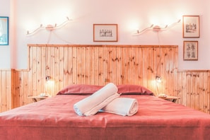 Une pièce aux murs lambrés, comprenant un lit, deux tables de chevet et des luminaires fixés au mur.