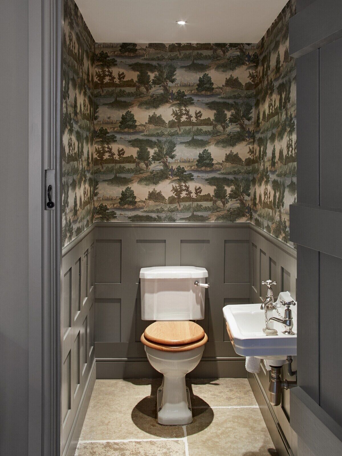 Un bagno con il water, un lavandino e carta da parati fantasia.