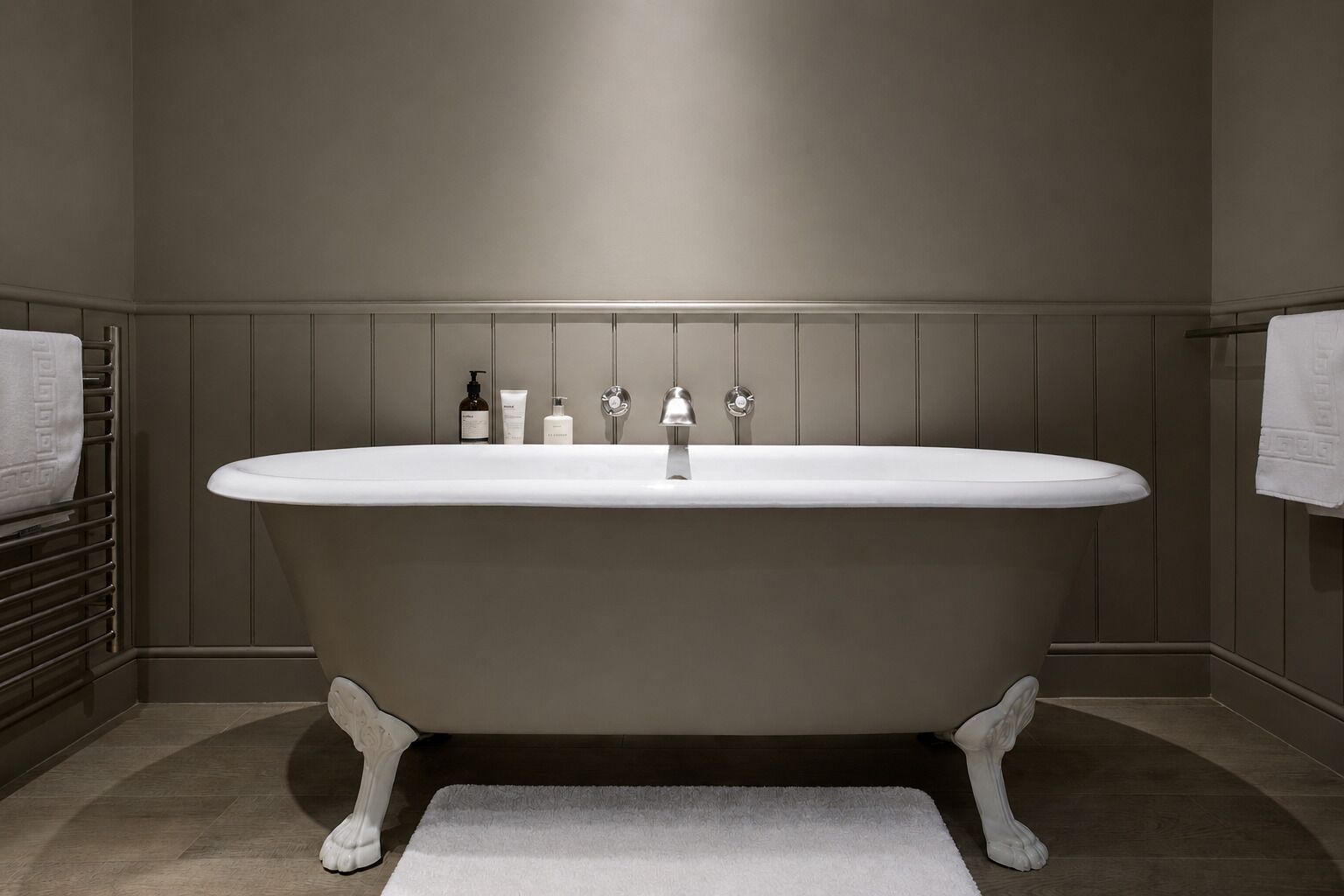 Ein modernes Badezimmer mit einer freistehenden Badewanne, einem Handtuchhalter und Pflegeprodukten an der Wand.