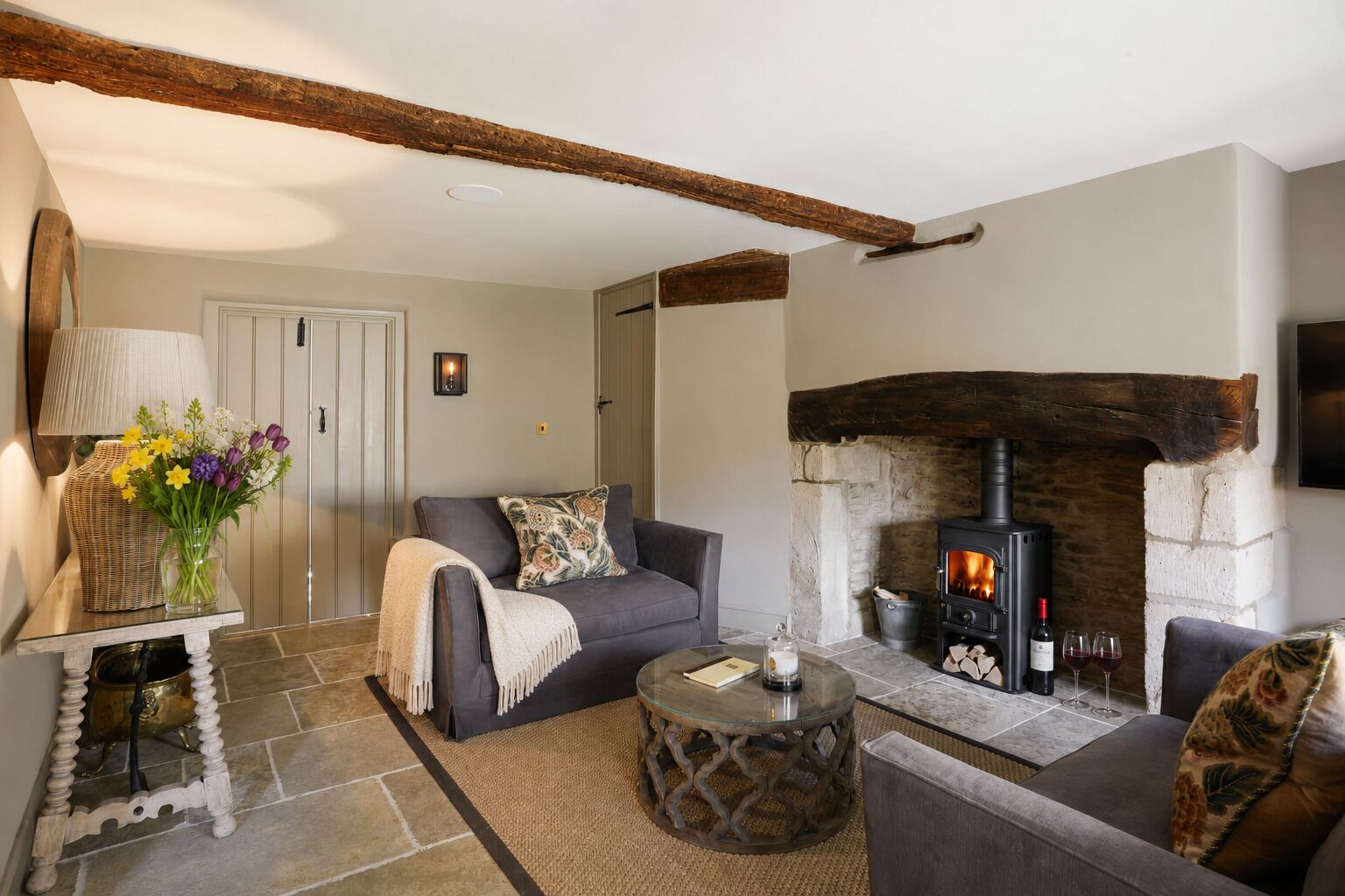 A cozy living room with a fireplace, a sofa, a coffee table, and a lamp.