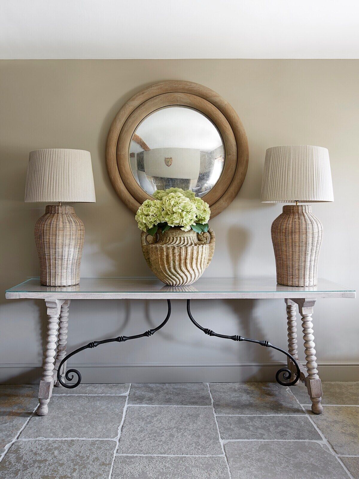 A console table with two lamps, a mirror, and a vase with flowers.