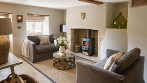 A cozy living room with a fireplace, two sofas, a coffee table, and a stone wall.