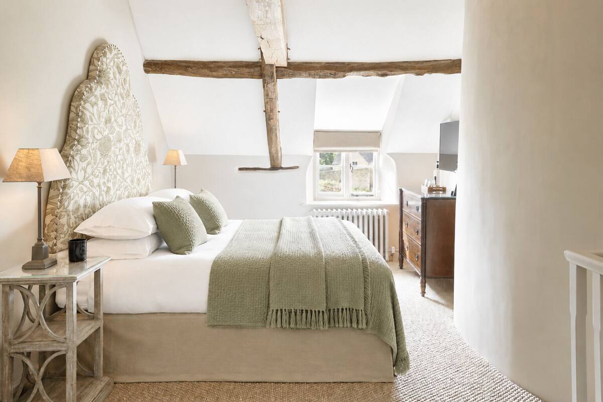 A bedroom with a bed, bedside tables, a dresser, a radiator, and a window.