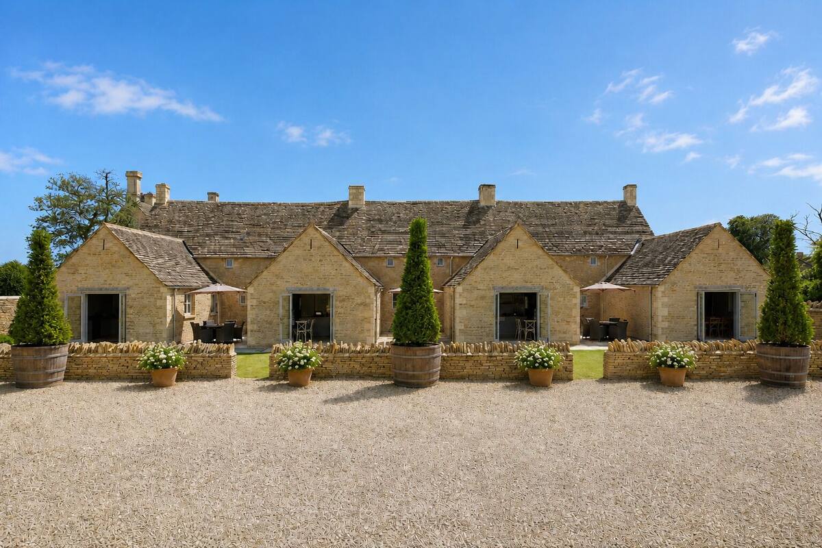 A stone building with multiple rooms, a gravel courtyard, and potted plants.