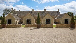 A row of stone buildings with multiple doors and windows, surrounded by gravel and potted plants.