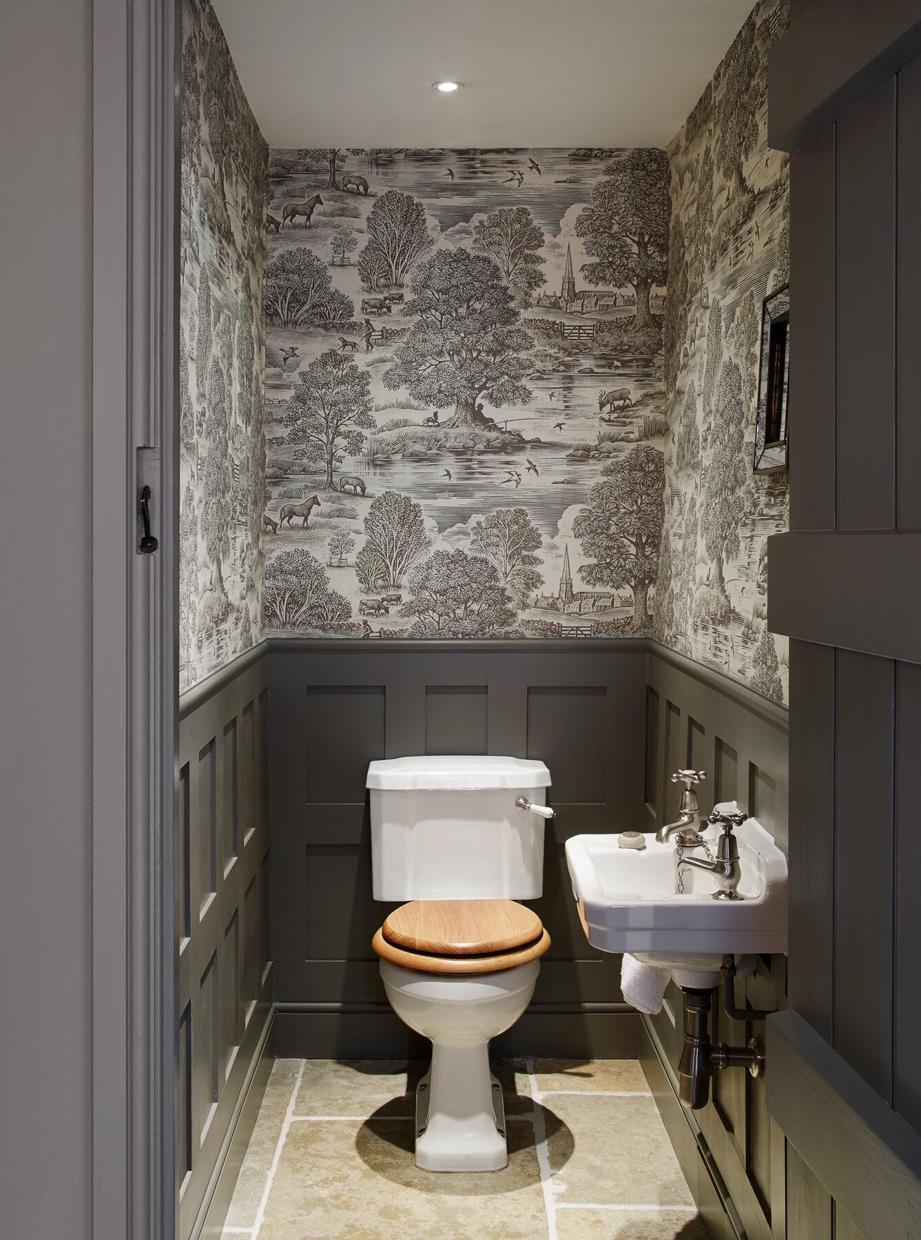 Un bagno con servizi igienici, lavandino e carta da parati decorata.